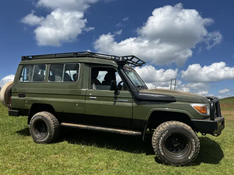 green landcruiser roadtrip kenya on grass blue sky