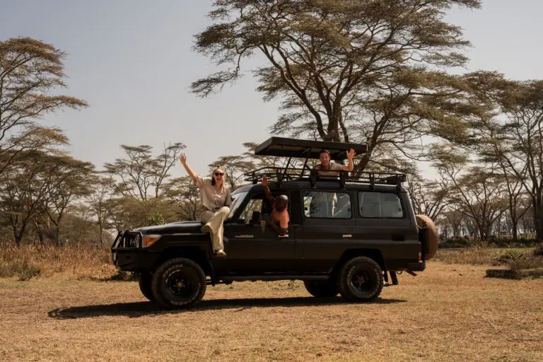 three happy people on a safari jeep in Kenya