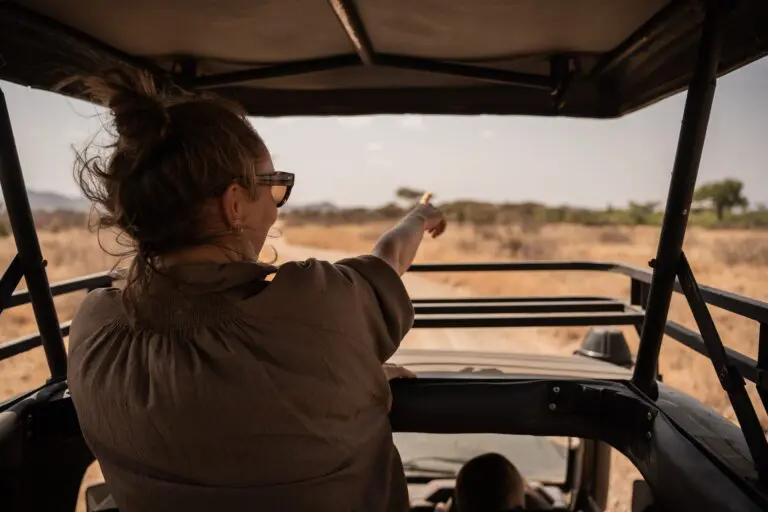 woman pointing from safari vehicle on a dry landscape