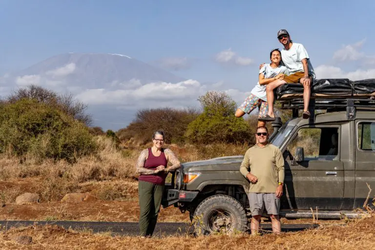 four people with safari vehicle and Mount Kilimanjaro in background